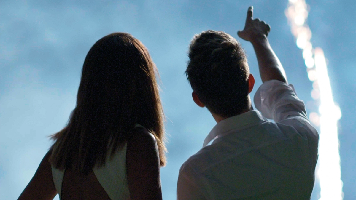 Kevin Chomat and his friend are in silhouette. Kevin points to the blue sky and the condensation streaks.