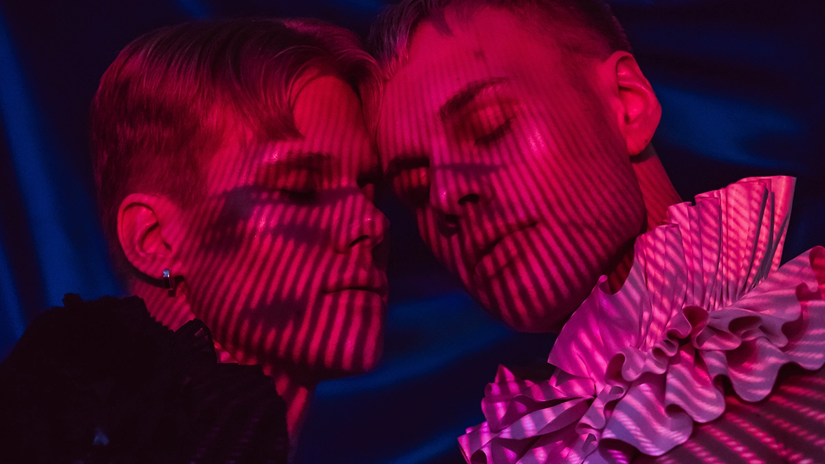 Nordik Sonar in a pink light with striped shadows, eyes closed.