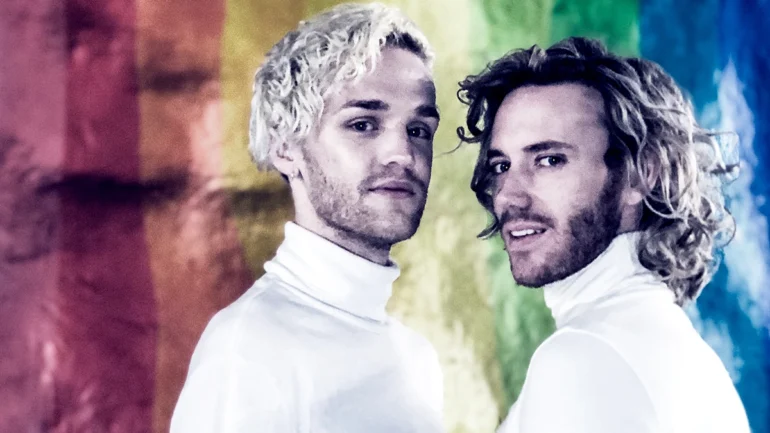 The Lovers of Valdaro stand in front of an LGBTQ flag, wearing white polos.