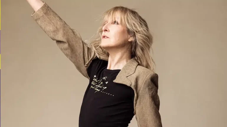 Donna Lewis's hand reaching towards the sky. Wearing a black and goldish beige long-sleeved shirt.