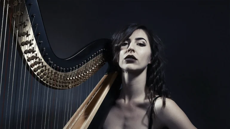 Stephanie Babirak sitting with her harp in a black dress.
