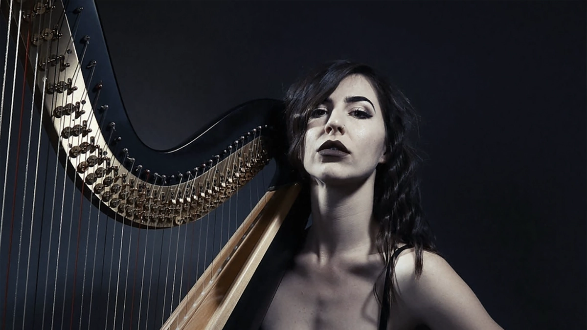 Stephanie Babirak sitting with her harp in a black dress.